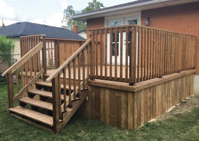 Wooden deck design with wooden railing and stairs in residential backyard