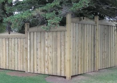 Wooden fence enclosing a residential backyard with trees
