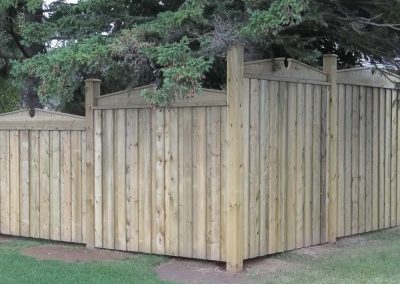 Wooden fence enclosing a residential backyard with trees