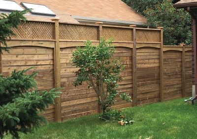 Wooden residential backyard fence with privacy lattice and planted trees