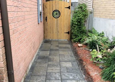 Interlocking stone residential backyard pathway with a wooden gate